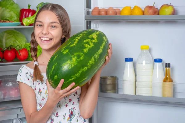 Menina com comida perto da geladeira — Fotografia de Stock