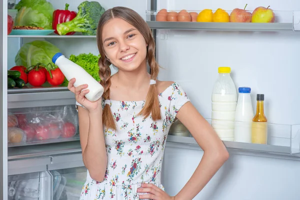 Красивая Молодая Девушка Держит Бутылку Молока Стоя Рядом Открытым Холодильником — стоковое фото