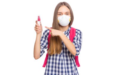 Koronavirüs karantinası kavramı. Grip virüsü sırasında el dezenfeksiyonu için antibakteriyel antiseptik spreyli tıbbi koruyucu maske takan bir çocuk. COVID-19. Öğrenci genç kız beyazda izole edilmiş.