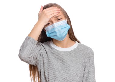 Koronavirüs karantinası kavramı. Hasta çocuk yüksek sıcaklıkta tıbbi koruyucu yüz maskesi takıyor. COVID-19, ev izolasyonu. Koronavirüs semptomu olan üzgün genç kız beyaz arka planda izole edilmiş.