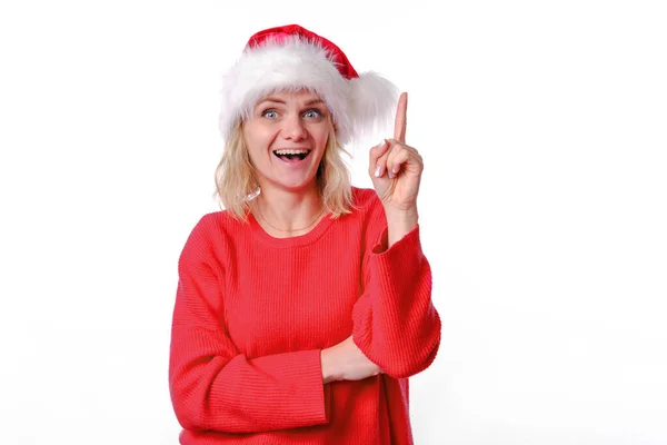 Höja finger eureka gest. Förvirrad fascinerad ung kvinna ler i röd jul Santa hatt. Känslomässig flicka står pekande upp finger se otroligt bra PR-försäljning. På vitt — Stockfoto