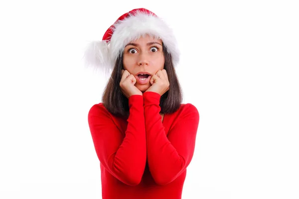 Chockad panik kvinna i röd jul Santa hatt höra häpnadsväckande nyheter, ser orolig och chockad, stirra kameran stå vit bakgrund förvånad inse sanningen, vit bakgrund — Stockfoto
