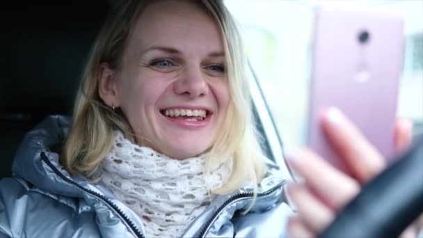 Jonge vrouw blogger in de winter kleren zitten in de auto en praten met volgers, live streaming, op zoek naar smartphone scherm. Sociale media, instagram, videochat en technologie concept — Stockvideo