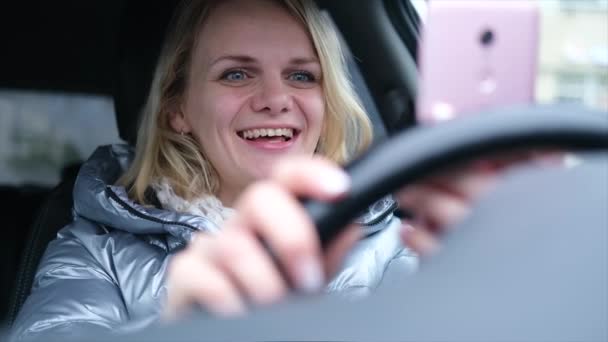 Mujer joven blogger en ropa de invierno sentada en coche y hablando con sus seguidores, transmisión en vivo, mirando a la pantalla del teléfono inteligente. Redes sociales, instagram, video chat y concepto de tecnología — Vídeo de stock