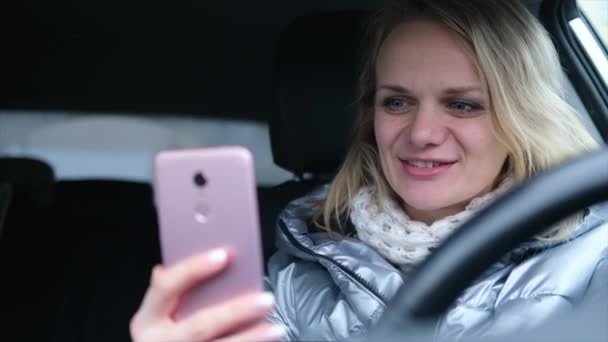 Giovane blogger in abiti invernali seduta in auto e parlare con i seguaci, in diretta streaming, cercando di schermo smartphone. Social media, instagram, video chat e concetto tecnologico — Video Stock