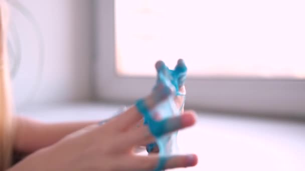 少女側に青いスライムストレッチ。子供たちは粘菌遊びをします白でスライムを作る。傾向のある液体おもちゃは手と指に固執する。4k映像 — ストック動画