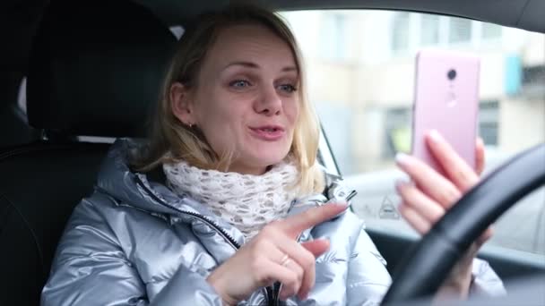 Giovane blogger in abiti invernali seduta in auto e parlare con i seguaci, in diretta streaming, cercando di schermo smartphone. Social media, instagram, video chat e concetto tecnologico — Video Stock