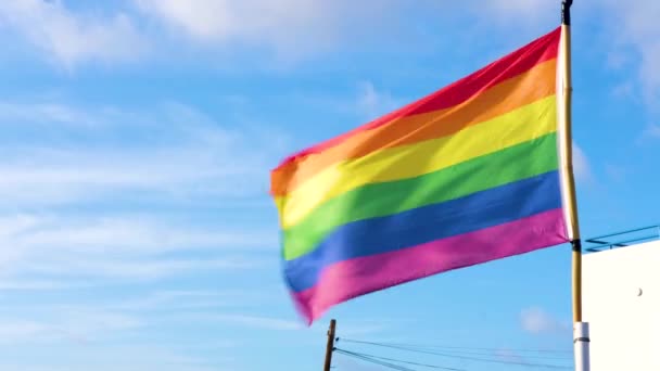 Yakından bakınca, Lgbt topluluğunun bir Avrupa şehrindeki gururunun sembolü olan Gay Gurur Gökkuşağı Bayrağı sallanıyor. Mavi gökyüzünde. İnsan hakları, eşitlik, Lgbt. 4k görüntü — Stok video