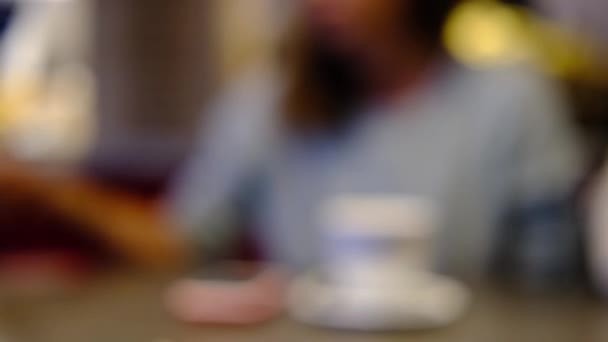 Blurred cropped young woman talks, tells interesting things and gestures with her hands with white cup of coffee in restaurant, cafe. Dark warm toned scene. — Stock Video