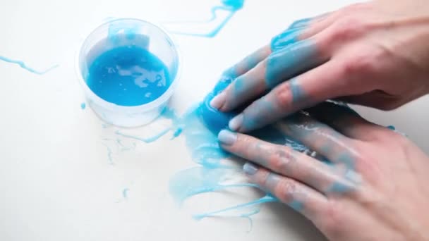 Menina esticando lodo azul para os lados. Mãos de mulher brincando de brinquedo viscoso. A fazer lodo no branco. Brinquedo líquido na moda adere a mãos e dedos. Filmagem 4k — Vídeo de Stock