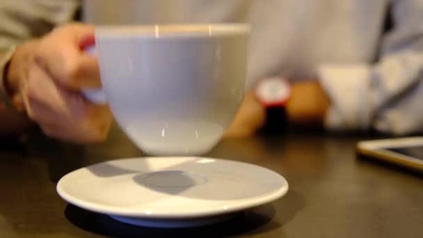 Café. Cortado joven mujer caucásica en gris beber café en el restaurante, cafetería. Primeros planos de las manos de las mujeres con copa blanca. Oscura escena tonificada cálida . — Vídeos de Stock