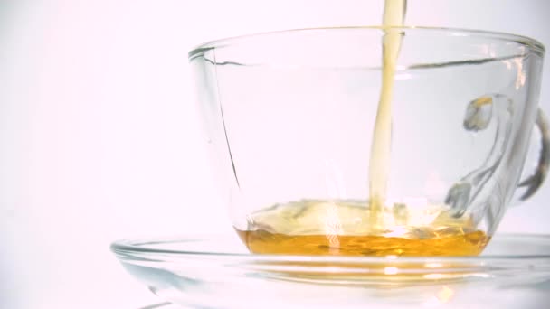 Verser le thé noir aromatisant de la théière dans une tasse de thé en verre transparent correspondant sur fond blanc gros plan .