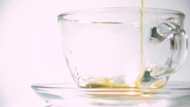 将茶壶中散发香味的红茶倒入白色背景特写的透明玻璃杯中. — 图库视频影像
