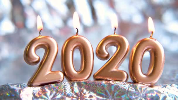 Text 2020 golden candles burning. Blurred silver background. Merry christmas and Happy New Year. Selective focus.Creative live greeting card. 4k footage — Stock Video