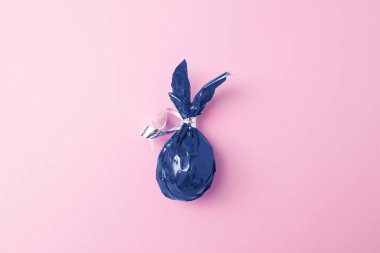 Pembe arka planda mavi yumurtalı tavşan kulaklı yaratıcı Paskalya tebrik kartı. Düz yatış, minimal stil, kopyalanma. 2020 'nin modası geçmiş klasik mavi rengi.