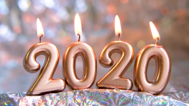 Text 2020 golden candles burning. Blurred silver background. Merry christmas and Happy New Year. Selective focus.Creative live greeting card. 4k footage — Stock Video