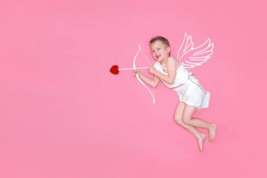 Mutlu gülümseyen bebek aşk meleği kanatları, pembe stüdyo arka planında izole edilmiş yay ve kalp oku. Metin için kopyalanma alanı. Sevgililer Günü konsepti
