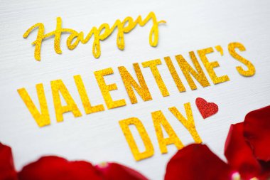 Sevgililer Günü 'nüz kutlu olsun. Kırmızı gül yaprakları ve beyaz ahşap kalpli tebrik kartı. romantik ve aşk konsepti