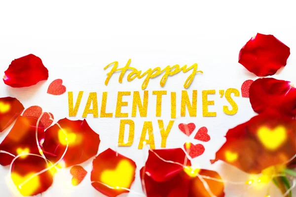 Поздравительная открытка на день святого Валентина с красными лепестками роз и сияющими сердцами на белом деревянном фоне. романтика и любовь — стоковое фото
