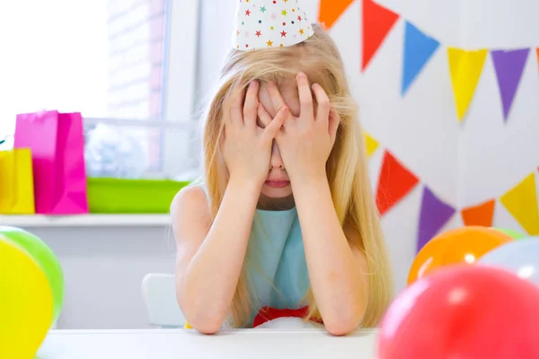 Infeliz rubia caucásica chica está llorando cerca de pastel de arco iris cumpleaños. Fondo colorido festivo. Mala fiesta de cumpleaños —  Fotos de Stock