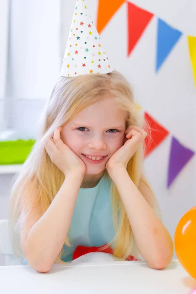 Retrato de chica rubia caucásica sonriendo en la fiesta de cumpleaños de la cámara. Fondo colorido festivo con globos. Foto vertical — Foto de Stock