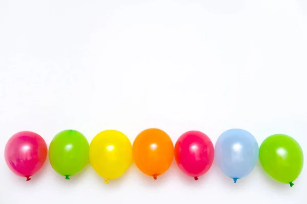 Colorful balloons on white wall or table top view. Festive or party background. Flat lay style. Copyspace for text. Birthday greeting card. — Stock Photo, Image