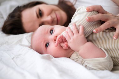 Anne sevgisi. Beyaz tenli, genç, esmer kadın anne. Yatakta yatan en tatlı bebeğine bakıyor. Küçük bir çocuk. Aile hayatı. Anne ve bebek. Mutlu annelik