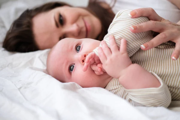 Moderskärlek. Vit ung brunett kvinna mamma tittar på sin lilla sötaste bebis liggande i sängen. Spädbarn. Familjeliv. Mor och barn. Lyckligt moderskap — Stockfoto