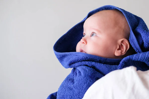 El bebé recién nacido caucásico envuelto en una toalla azul mira hacia un lado después de bañarse en el baño en los brazos de sus madres. Espacio de copia . — Foto de Stock