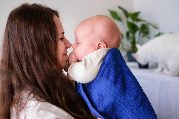 Mamá abraza a su bebé más lindo después del baño con toalla azul en la cabeza. Niño en manos de madre. Amor maternal. Vida familiar. Madre y bebé. Feliz maternidad. — Foto de Stock