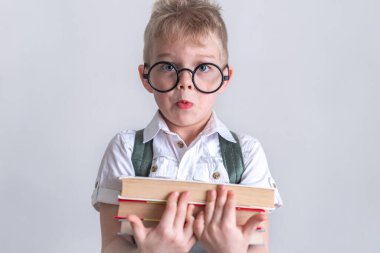 Okula dönelim. Portre, yuvarlak gözlüklü, kitaplı ve gri gömlekli sarışın çocuğu şaşırttı. Eğitim. Kameraya bakıyorum.