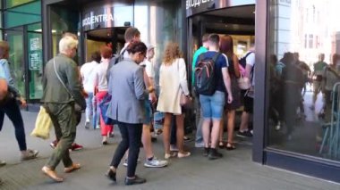 Çok ırklı bir kalabalık bir alışveriş merkezine, iş merkezine veya havaalanına cam kapılardan giriyor. Şehir yaz günü, şehir sakinleri ve turistler. Galeri merkezi. St. Petersburg 18Ağustos 2019