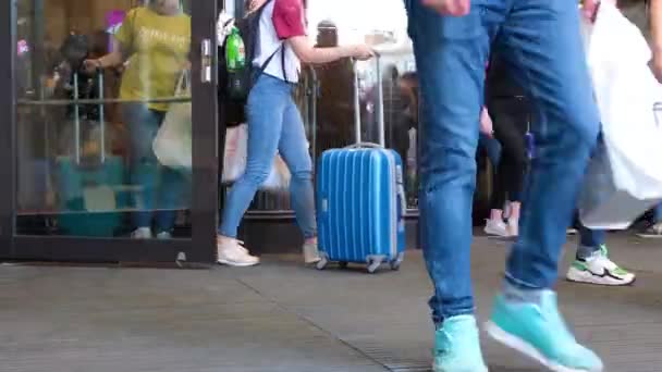 Crowd multiethnic people leave the building of shopping business center or airport through glass doors. Tourists with suitcases and bags. Legs close up. City summer day. St.Petersburg 18aug2019 — Stock Video