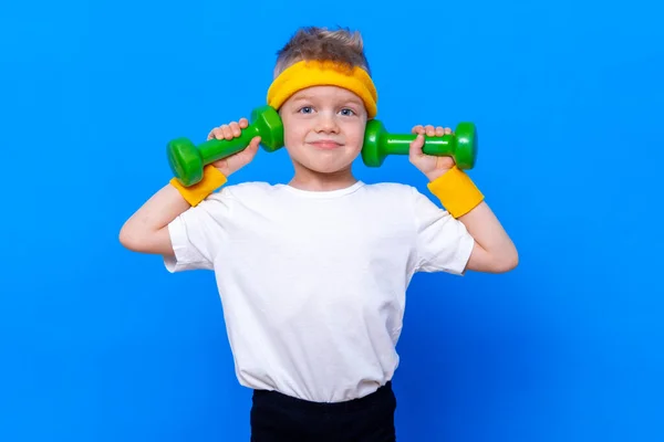 Fitness kind. Portret van een sportief jongetje met halters over een blauwe studioachtergrond. Gym training. Kindersportman. Jeugdactiviteit. Sport. Fitness, gezondheid en energie. Succes. — Stockfoto