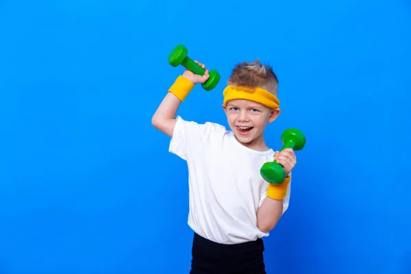 Fitness kind. Portret van een sportief jongetje met halters over een blauwe studioachtergrond. Gym training. Kindersportman. Jeugdactiviteit. Sport. Fitness, gezondheid en energie. Succes. — Stockfoto