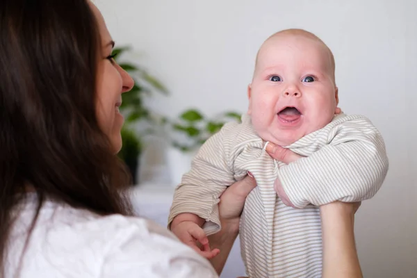 Feliz bebé. Pequeno bebê branco branco gordinha gordinha mais bonito olhando e sorrindo para a câmera nas mãos da mãe. Vida familiar, mães amam, maternidade — Fotografia de Stock