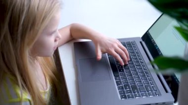 Küçük sarışın kız laptopta çalışıyor, çalışıyor ya da oyun oynuyor. Düğmelerdeki parmağa bas. Dijital eğitimler. Bilgisayar teknolojisi, sosyal medya ve internet. 4k görüntü