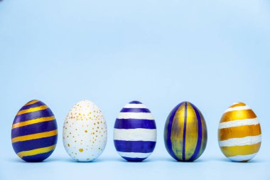 Beş Paskalya modası klasik mavi ve altın desenli yumurtalar mavi üzerine çizgili. Mesaj için fotokopi alanı olan mutlu Paskalyalar. Asgari biçim
