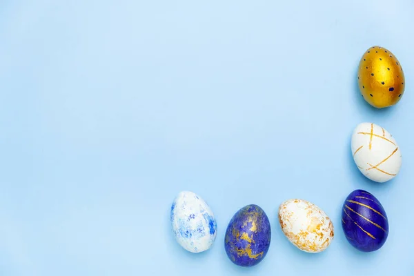 复活节快乐用复活节彩蛋制成的纯蓝色、白色和金色蓝色相间的文本框架。最小样式、顶视图、平铺、复制空间. — 图库照片