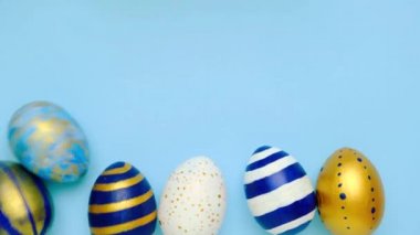 Paskalya yumurtaları yuvarlanıyor, birbirlerini mavi masaya vuruyorlar. Yumurtaların modası geçmiş klasik mavi, beyaz ve altın rengi. Mutlu Paskalyalar. Asgari düzeyde. Üst görünüm