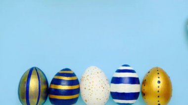 Paskalya yumurtaları yuvarlanıyor, birbirlerini mavi masaya vuruyorlar. Yumurtaların modası geçmiş klasik mavi, beyaz ve altın rengi. Mutlu Paskalyalar. Asgari düzeyde. Üst görünüm