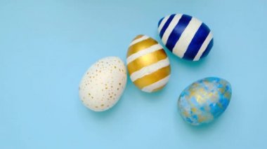 Paskalya yumurtaları yuvarlanıyor, birbirlerini mavi masaya vuruyorlar. Yumurtaların modası geçmiş klasik mavi, beyaz ve altın rengi. Mutlu Paskalyalar. Asgari düzeyde. Üst görünüm