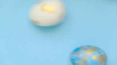 Paskalya yumurtası mavi masada dönüyor. Yumurta rengi klasik mavi, beyaz ve altın sarısı. Mutlu Paskalyalar. Asgari düzeyde. Üst görünüm