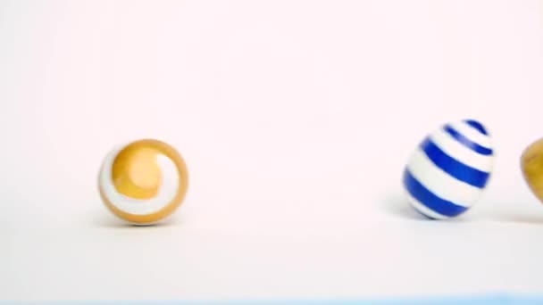 Paaseieren rollen, kloppen elkaar op de witte tafel. Eieren trendy gekleurd klassiek blauw, wit en goud. Vrolijk Pasen. Minimale stijl. — Stockvideo