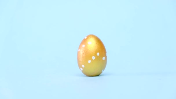 Jaja wielkanocne toczą się, pukając się na niebieski stół. Jaja modne kolorowe klasyczny niebieski, biały i złoty. Szczęśliwej Wielkanocy. Minimalny styl. — Wideo stockowe