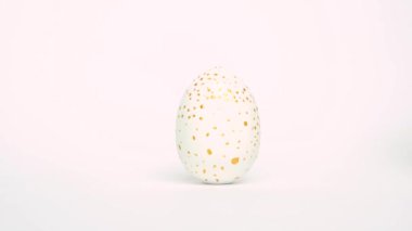 Paskalya yumurtaları yuvarlanıyor, birbirlerini beyaz masaya vuruyorlar. Yumurtaların modası geçmiş klasik mavi, beyaz ve altın rengi. Mutlu Paskalyalar. Asgari biçim. 