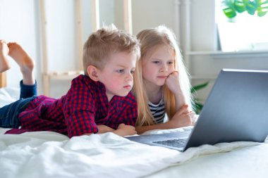 Uzaktan öğrenme çevrimiçi eğitim. Öğrenci çocuk ve kız evde dijital tablet dizüstü bilgisayarla ders çalışıyor ve okul ödevi yapıyor. Eğitim kitaplarıyla yatakta oturmak..