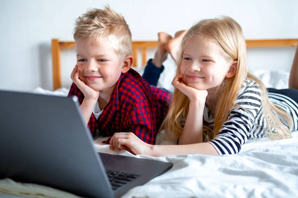Uzaktan öğrenme çevrimiçi eğitim. Öğrenci çocuk ve kız evde dijital tablet dizüstü bilgisayarla ders çalışıyor ve okul ödevi yapıyor. Eğitim kitaplarıyla yatakta oturmak..