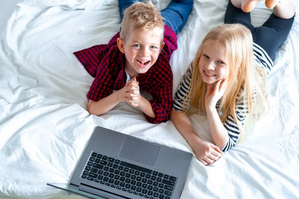 Enseignement à distance en ligne. vue du haut sur écolier et fille étudiant à la maison avec ordinateur portable tablette numérique ordinateur portable et faire des devoirs scolaires. Assis sur le lit avec des livres d'entraînement . — Photo