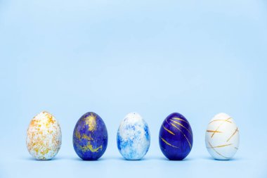 Mavi arka planda beş Paskalya modası klasik mavi ve altın madalyalı yumurta. Mesaj için fotokopi alanı olan mutlu Paskalyalar. Asgari paskalya biçimi